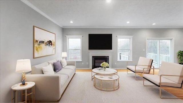 living room featuring crown molding, baseboards, recessed lighting, wood finished floors, and a glass covered fireplace