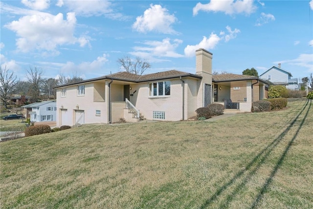 back of house featuring a yard, brick siding, and a chimney
