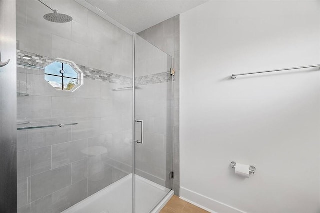 bathroom with tile patterned flooring, a stall shower, and baseboards