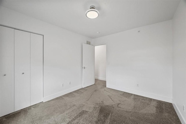 unfurnished bedroom featuring a closet, baseboards, visible vents, and carpet flooring