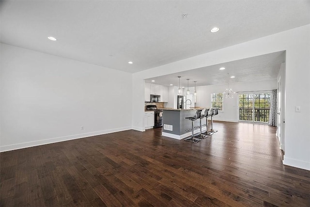 living area with dark wood-style floors, recessed lighting, baseboards, and an inviting chandelier