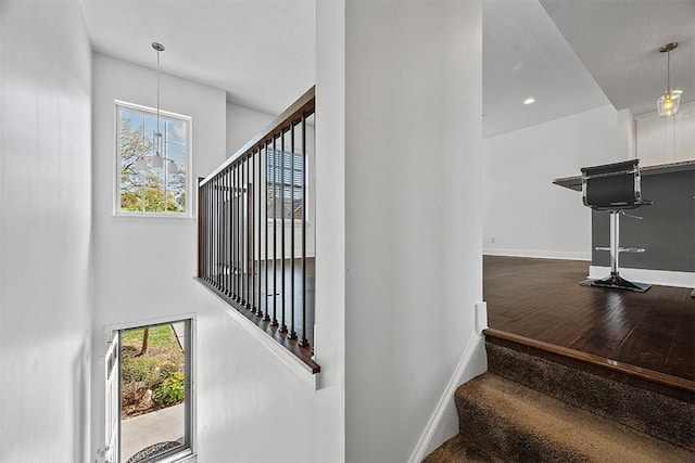 staircase with plenty of natural light, wood finished floors, and baseboards