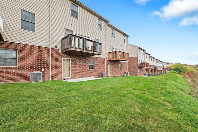 back of house with brick siding, central air condition unit, and a lawn