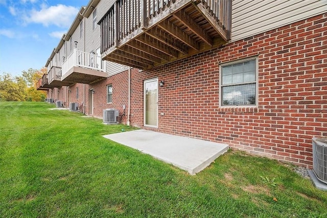 exterior space with brick siding, central AC unit, and a lawn