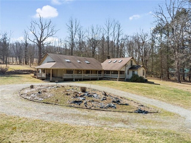 view of front of property with curved driveway, a porch, and a front lawn
