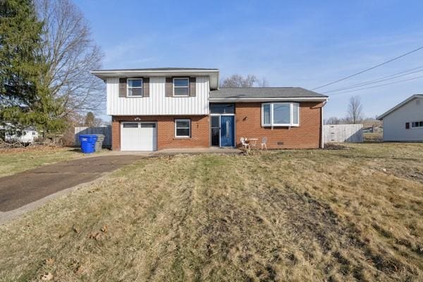 tri-level home with driveway, a front lawn, fence, an attached garage, and brick siding