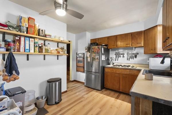 kitchen with brown cabinets, gas stovetop, freestanding refrigerator, and a sink