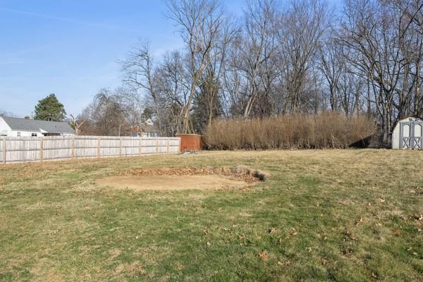 view of yard featuring an outbuilding, a shed, and fence