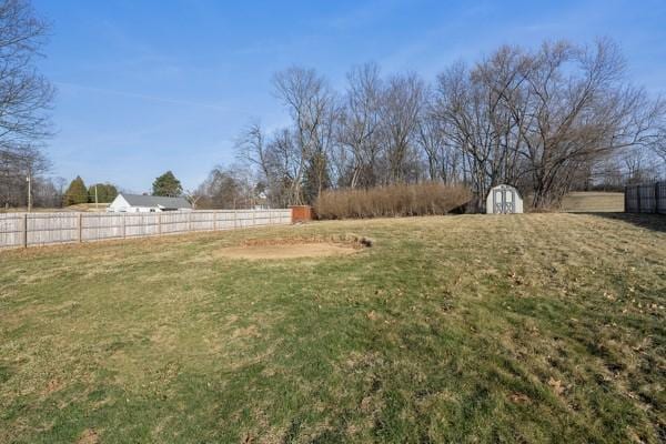 view of yard featuring an outbuilding, a rural view, a storage unit, and fence