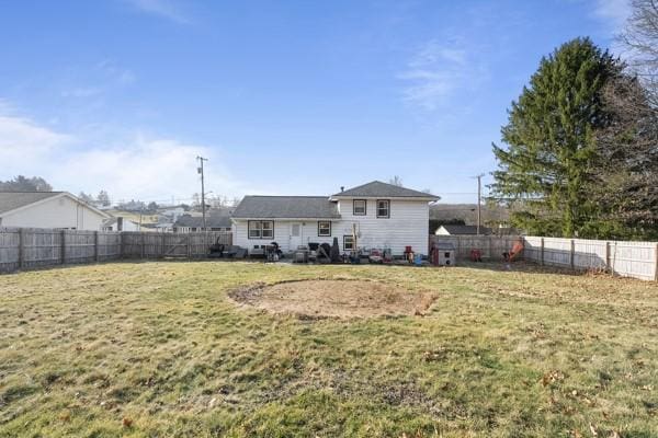 rear view of property featuring a fenced backyard and a yard