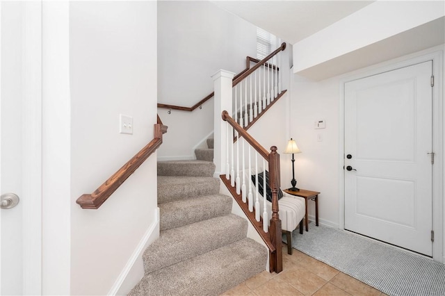 foyer entrance featuring stairway, light tile patterned floors, and baseboards