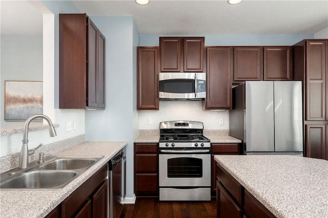 kitchen featuring dark wood-type flooring, a sink, tasteful backsplash, appliances with stainless steel finishes, and light countertops