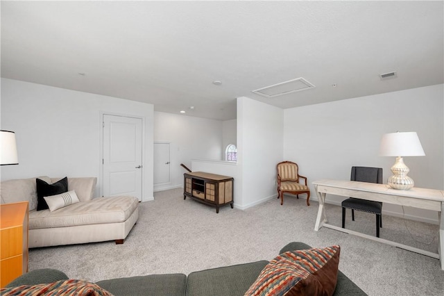 carpeted living area featuring visible vents, baseboards, and attic access