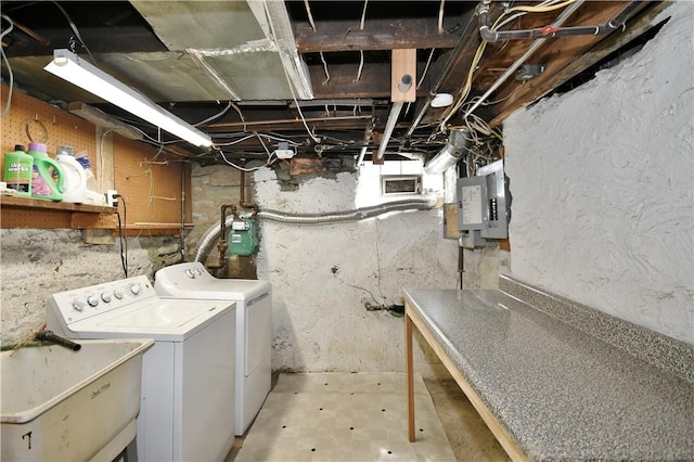 washroom featuring electric panel, laundry area, washer and dryer, and a sink