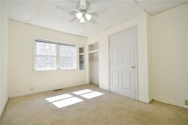 unfurnished bedroom with a closet, carpet flooring, a ceiling fan, and visible vents