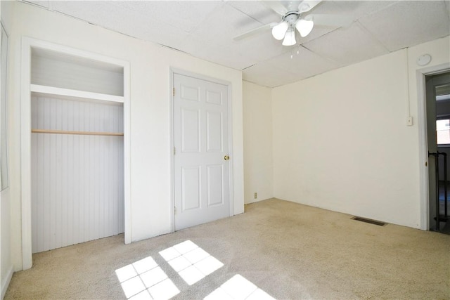 unfurnished bedroom with visible vents, carpet, and a ceiling fan