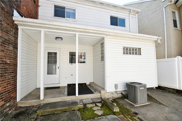 view of exterior entry with central AC unit and fence