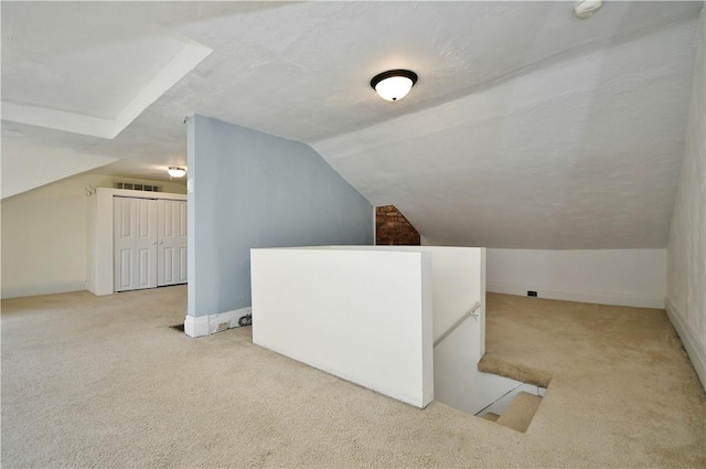 additional living space featuring a textured ceiling, visible vents, carpet, and vaulted ceiling