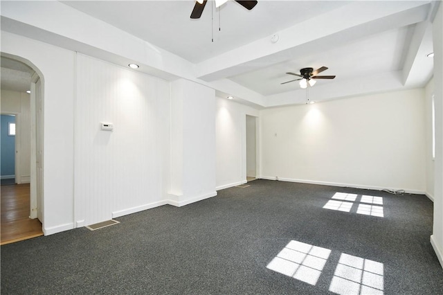 unfurnished room with baseboards, visible vents, a tray ceiling, arched walkways, and ceiling fan