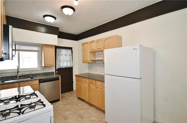 kitchen featuring light brown cabinets, white appliances, dark countertops, and a sink