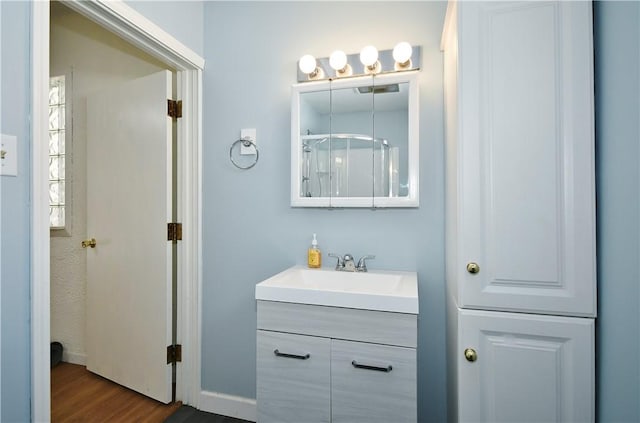 bathroom featuring walk in shower, wood finished floors, and vanity