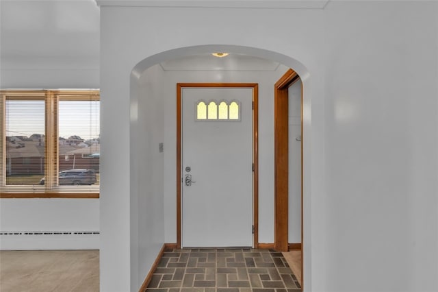 foyer entrance featuring a wealth of natural light, baseboards, arched walkways, and baseboard heating