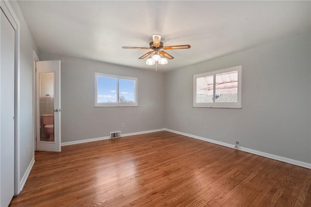 unfurnished bedroom featuring multiple windows, wood finished floors, and visible vents