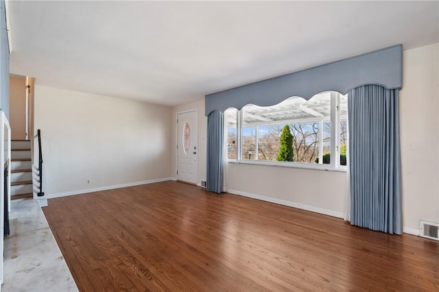 unfurnished living room with wood finished floors and baseboards