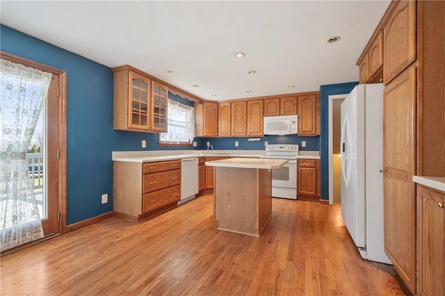 kitchen featuring light wood-type flooring, brown cabinets, white appliances, light countertops, and glass insert cabinets