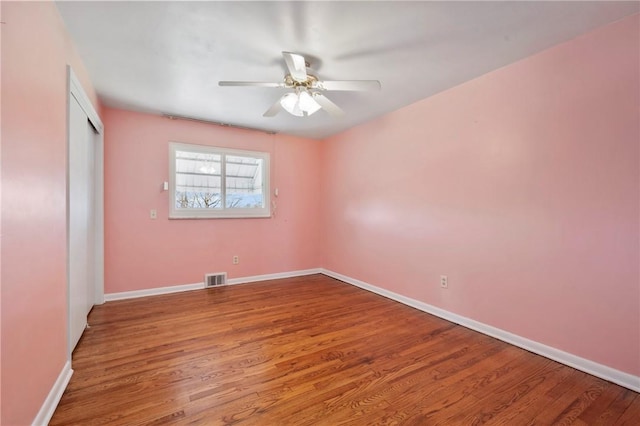 unfurnished bedroom with a ceiling fan, wood finished floors, visible vents, baseboards, and a closet