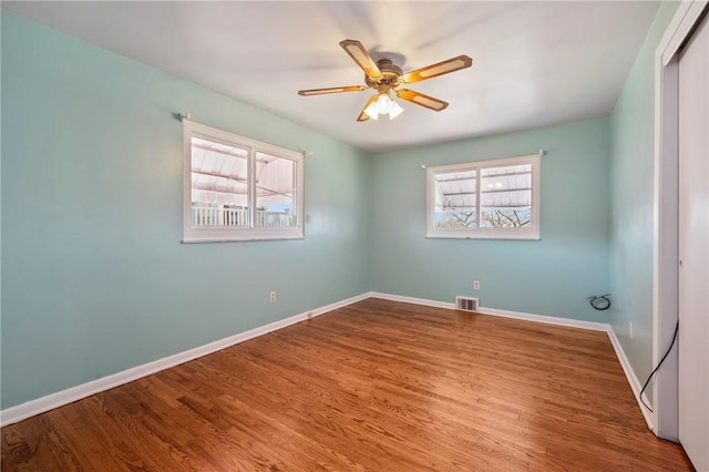 spare room featuring a healthy amount of sunlight, ceiling fan, baseboards, and wood finished floors