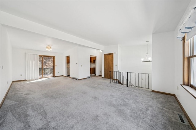 empty room featuring visible vents, carpet floors, baseboards, and a chandelier