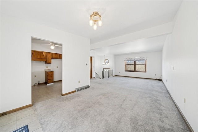 unfurnished living room with light tile patterned floors, light colored carpet, visible vents, and baseboards