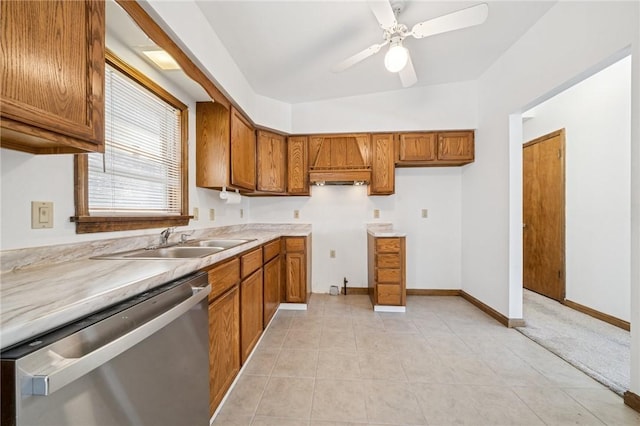 kitchen with a sink, dishwasher, brown cabinetry, and light tile patterned floors