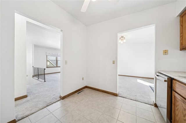 interior space featuring baseboards, light colored carpet, visible vents, and ceiling fan