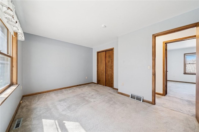 carpeted spare room with visible vents and baseboards