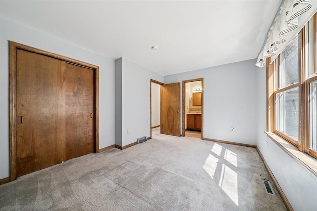 unfurnished bedroom featuring light carpet, visible vents, a closet, and baseboards