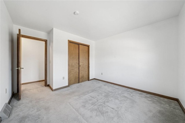 unfurnished bedroom featuring light carpet, visible vents, a closet, and baseboards