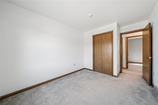 unfurnished bedroom with visible vents, light colored carpet, baseboards, and a closet