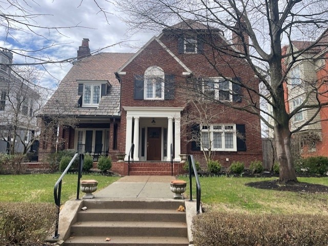 view of front of house featuring a front yard, brick siding, and a chimney