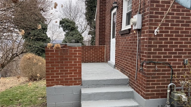 exterior space with brick siding, electric meter, and gas meter