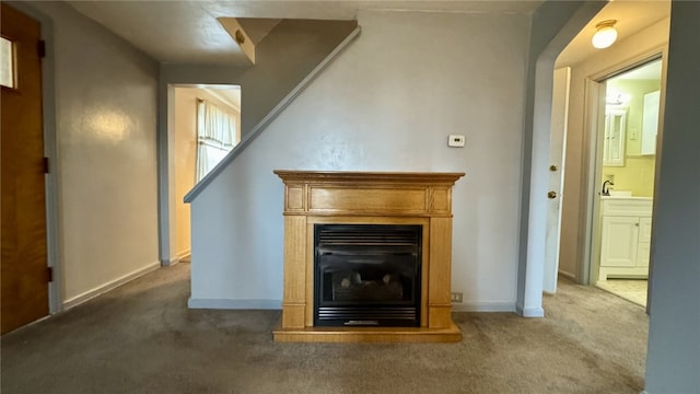 unfurnished living room featuring a sink, baseboards, a glass covered fireplace, and carpet flooring