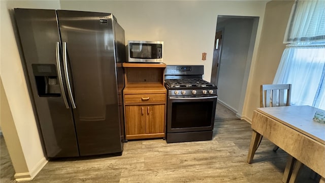 kitchen featuring brown cabinets, appliances with stainless steel finishes, baseboards, and light wood-style floors