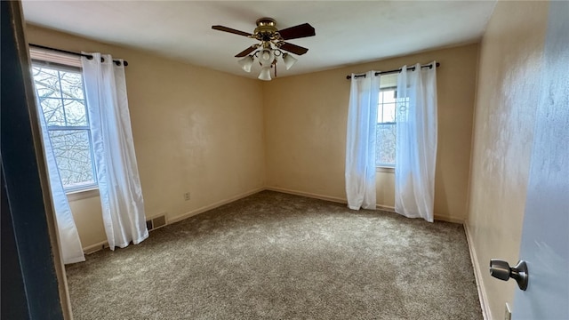 carpeted spare room featuring visible vents, baseboards, and ceiling fan