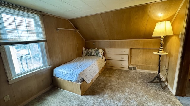 carpeted bedroom featuring vaulted ceiling, wooden walls, and visible vents