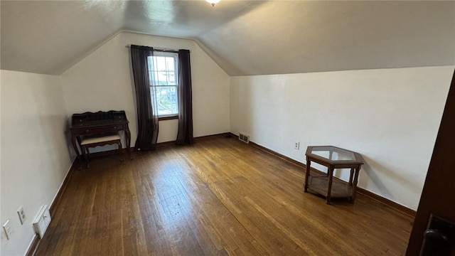 additional living space with visible vents, lofted ceiling, dark wood-type flooring, and baseboards