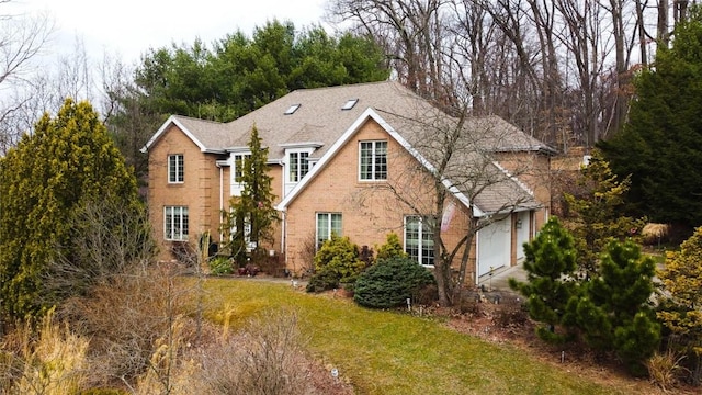 view of front of house featuring a garage, brick siding, a front yard, and a shingled roof