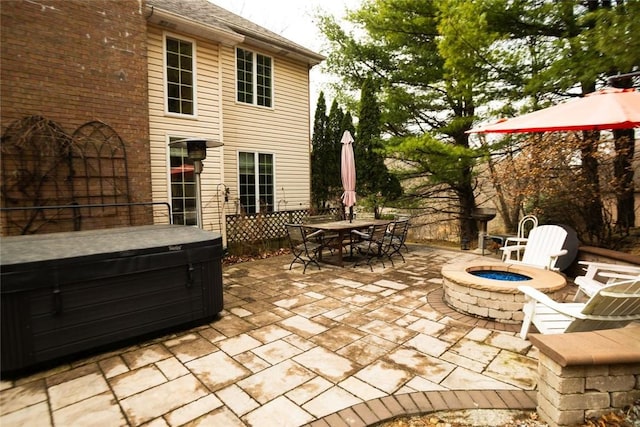 view of patio with outdoor dining area, an outdoor fire pit, and a hot tub