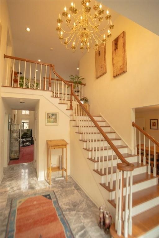 staircase with recessed lighting, a notable chandelier, marble finish floor, and a towering ceiling