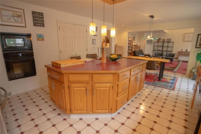 kitchen featuring a center island, open floor plan, light floors, pendant lighting, and black appliances